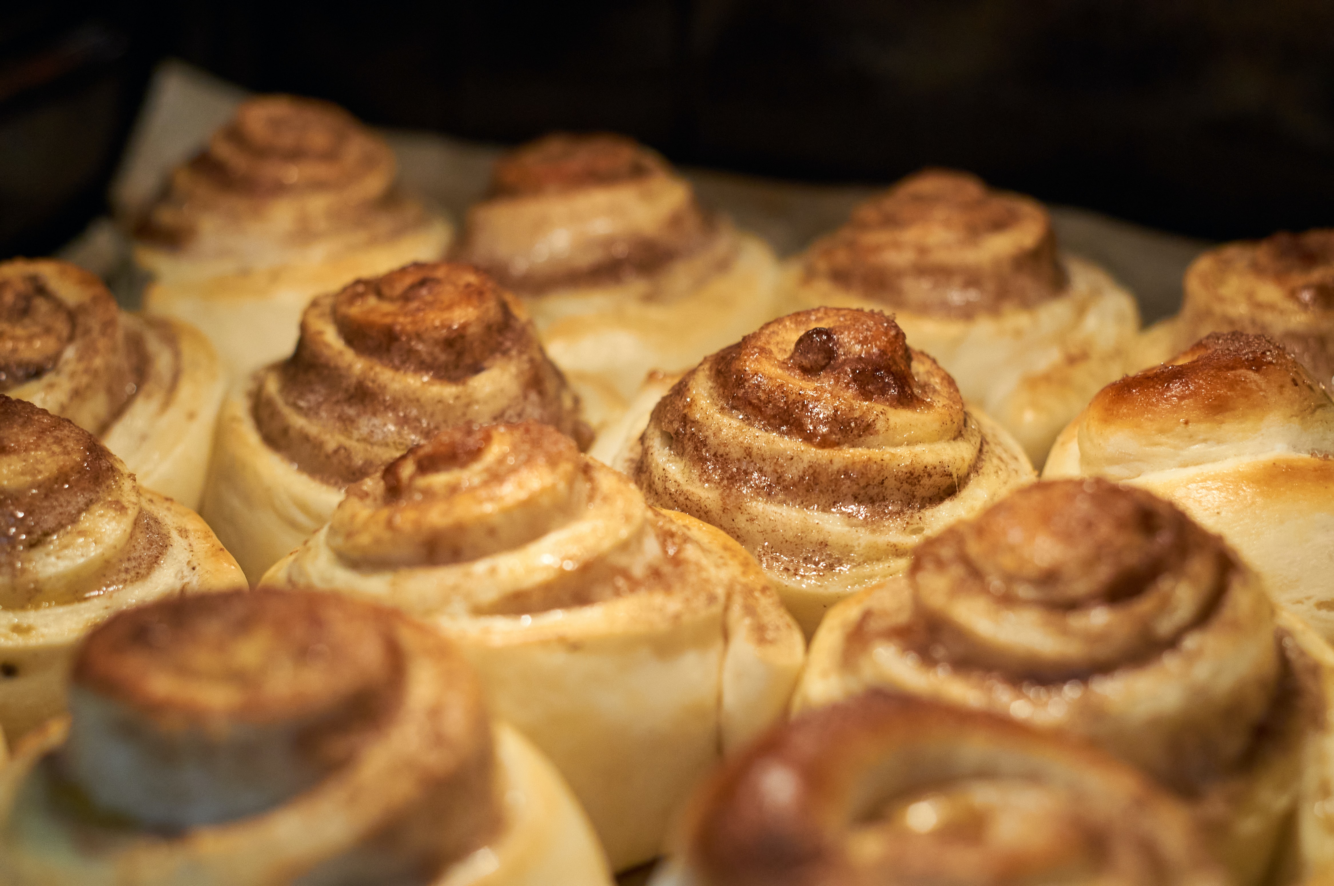 close up photo of cinnamon rolls on a baking sheet in the oven