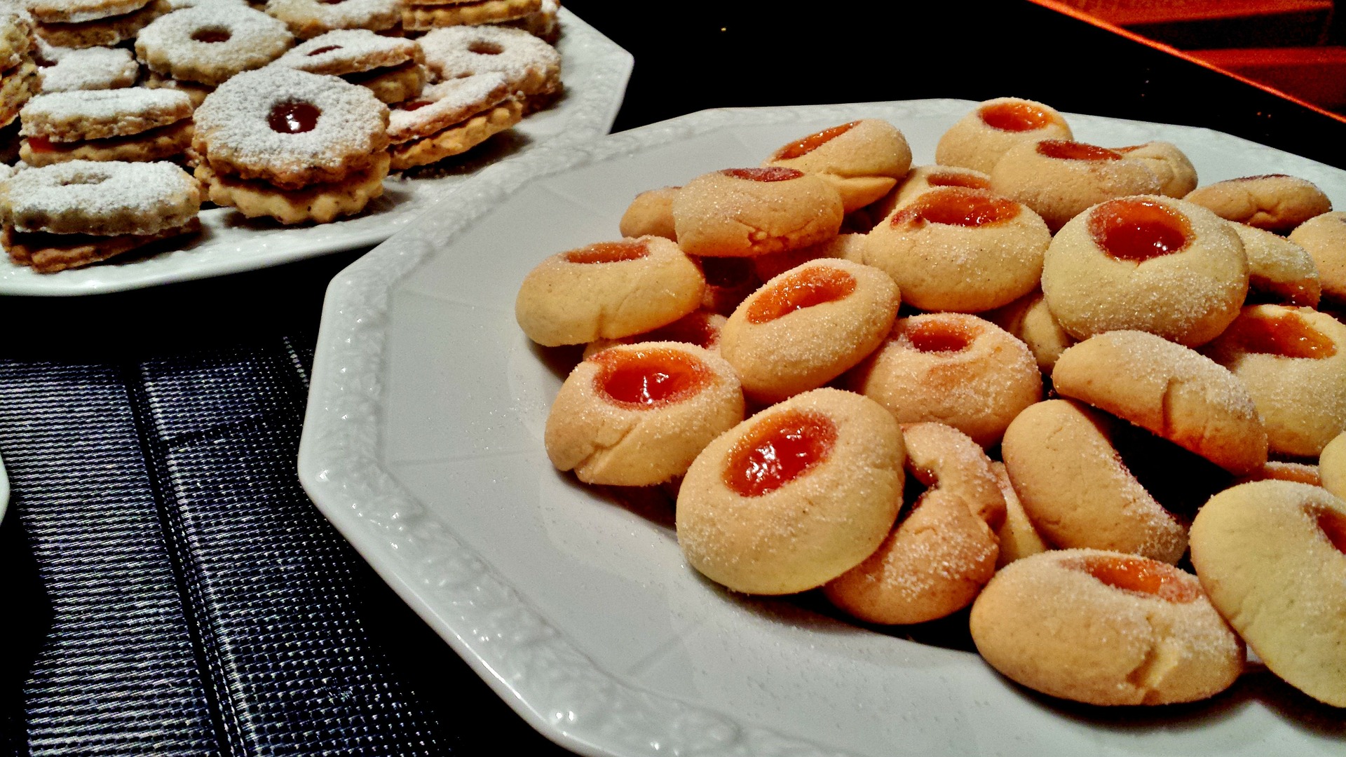 photo of thumbprint jam cookies on a plate to the right of another type of jam cookie